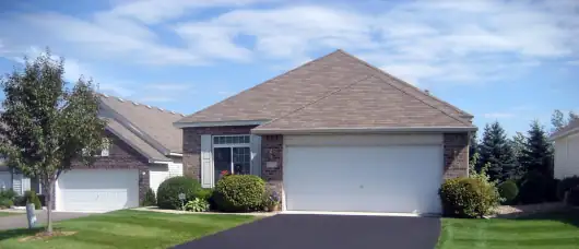 Well-maintained suburban home with fresh asphalt driveway and manicured lawn.